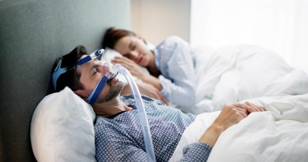 man sleeping with sleep apnea treatment mask